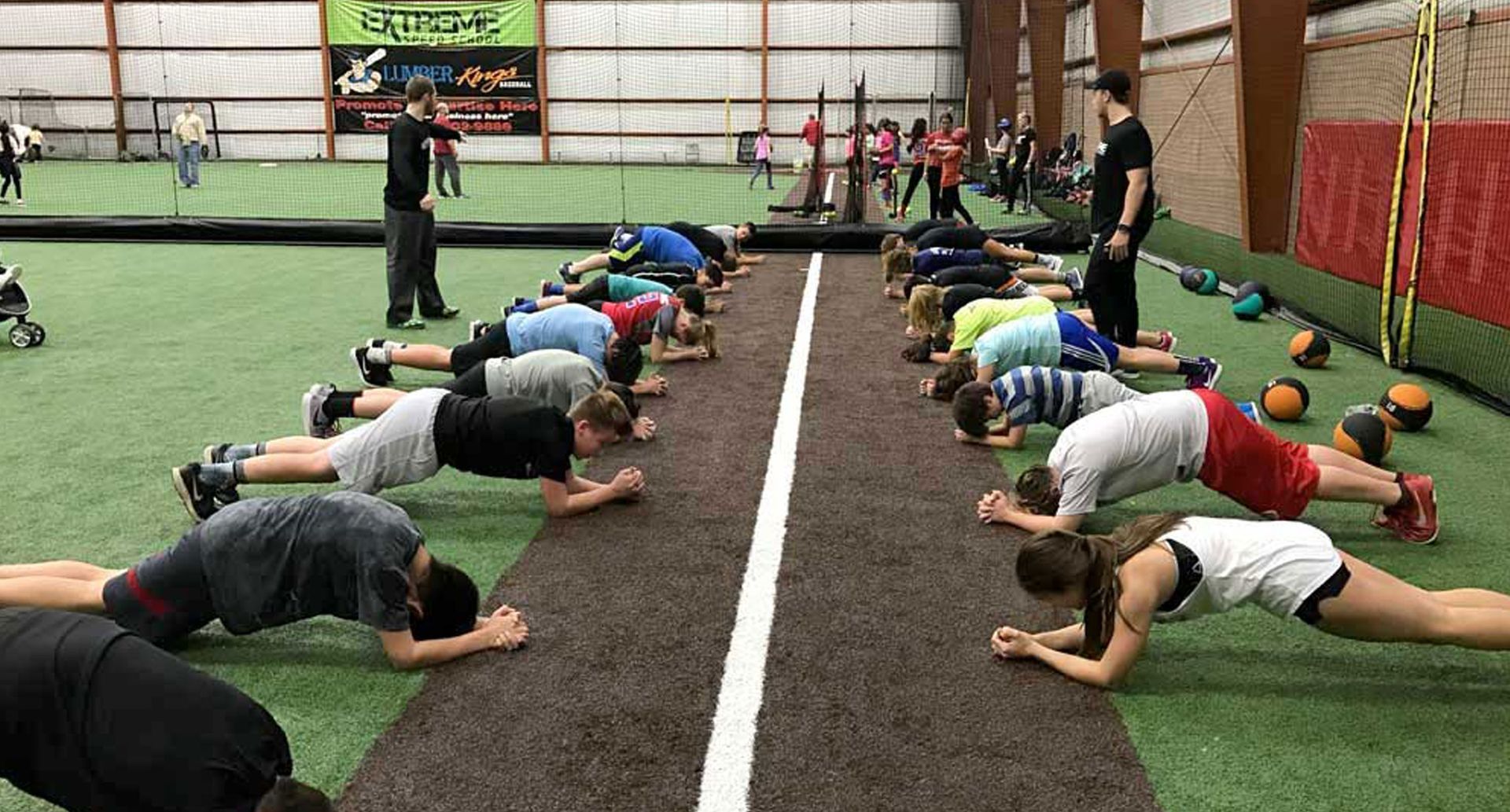 Indoor sports training facility with turf, cages, and protective netting.