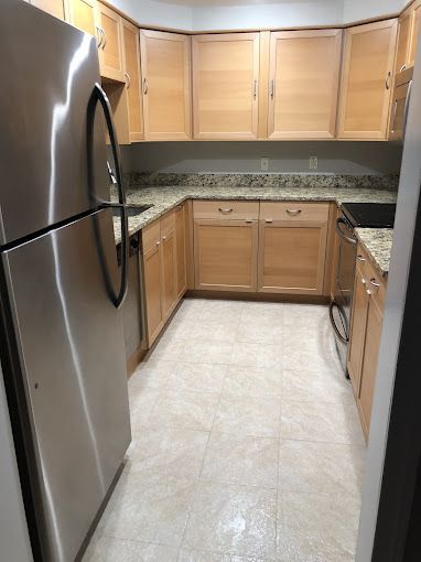 Kitchen with light wood cabinets, stainless steel appliances, and beige countertops.
