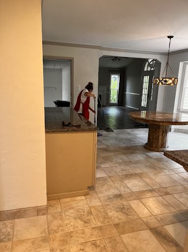 Interior view of a kitchen, dining, and living room space. Person cleaning near countertop.
