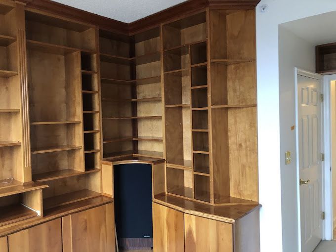 Wooden built-in bookshelves in a corner, with cabinets below. Light wood with brown trim.