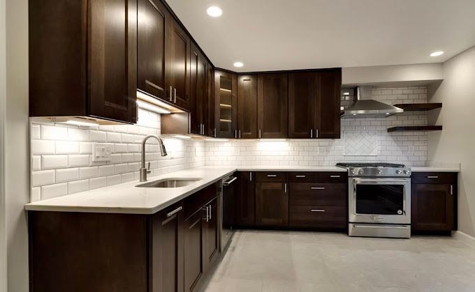 Dark-stained cabinets in a modern kitchen with white countertops, subway tile backsplash, and stainless steel appliances.