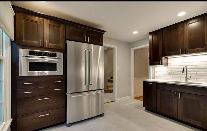 Dark wood kitchen with stainless steel appliances, light counter, and subway tile backsplash.