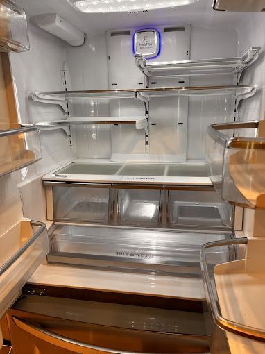 Empty refrigerator interior with clear shelves, drawers, and lighting.
