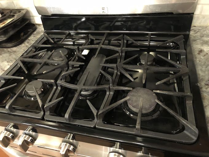Black gas stovetop with six burners and a stainless steel body.