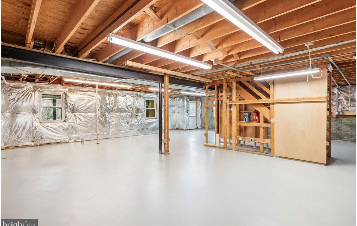 Finished basement with exposed wood beams, insulation, and concrete floor.