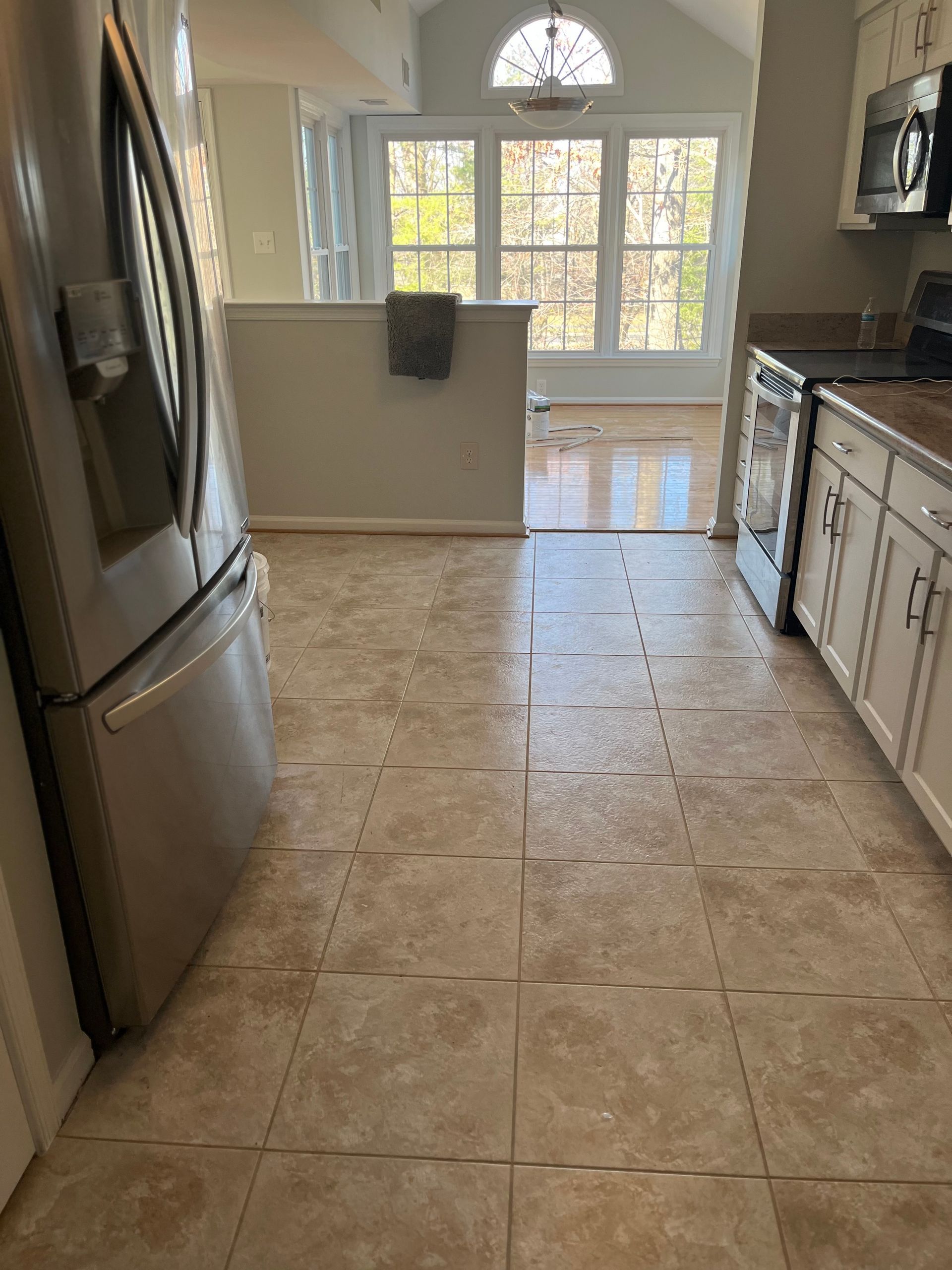 Kitchen with tile floor, stainless steel fridge, white cabinets, and a windowed dining area.