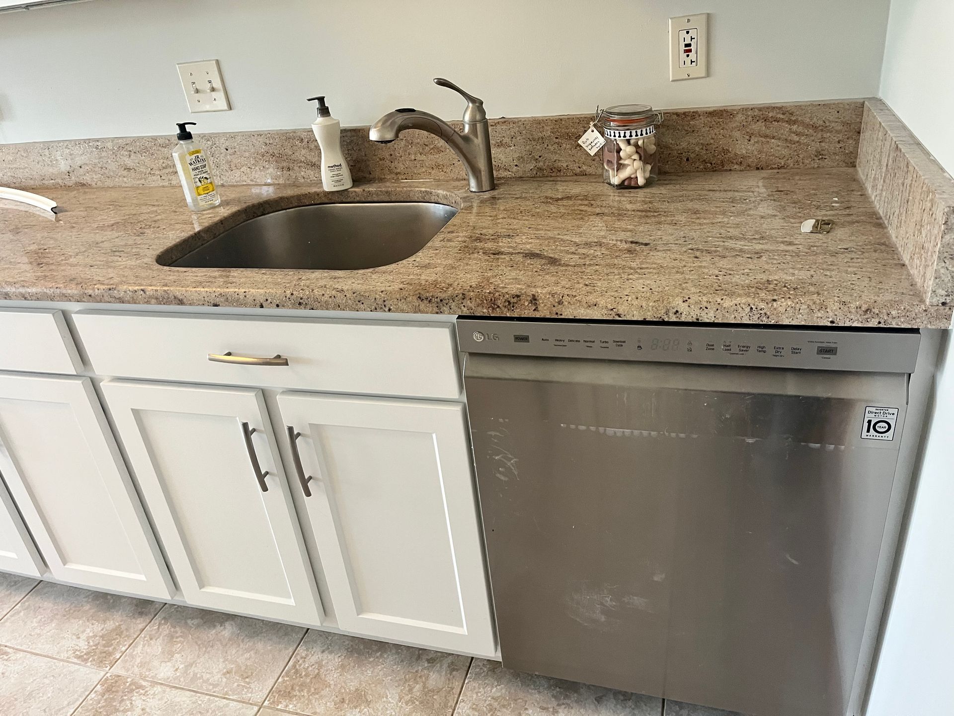 Kitchen with a stainless steel sink, dishwasher, white cabinets, and granite countertop.