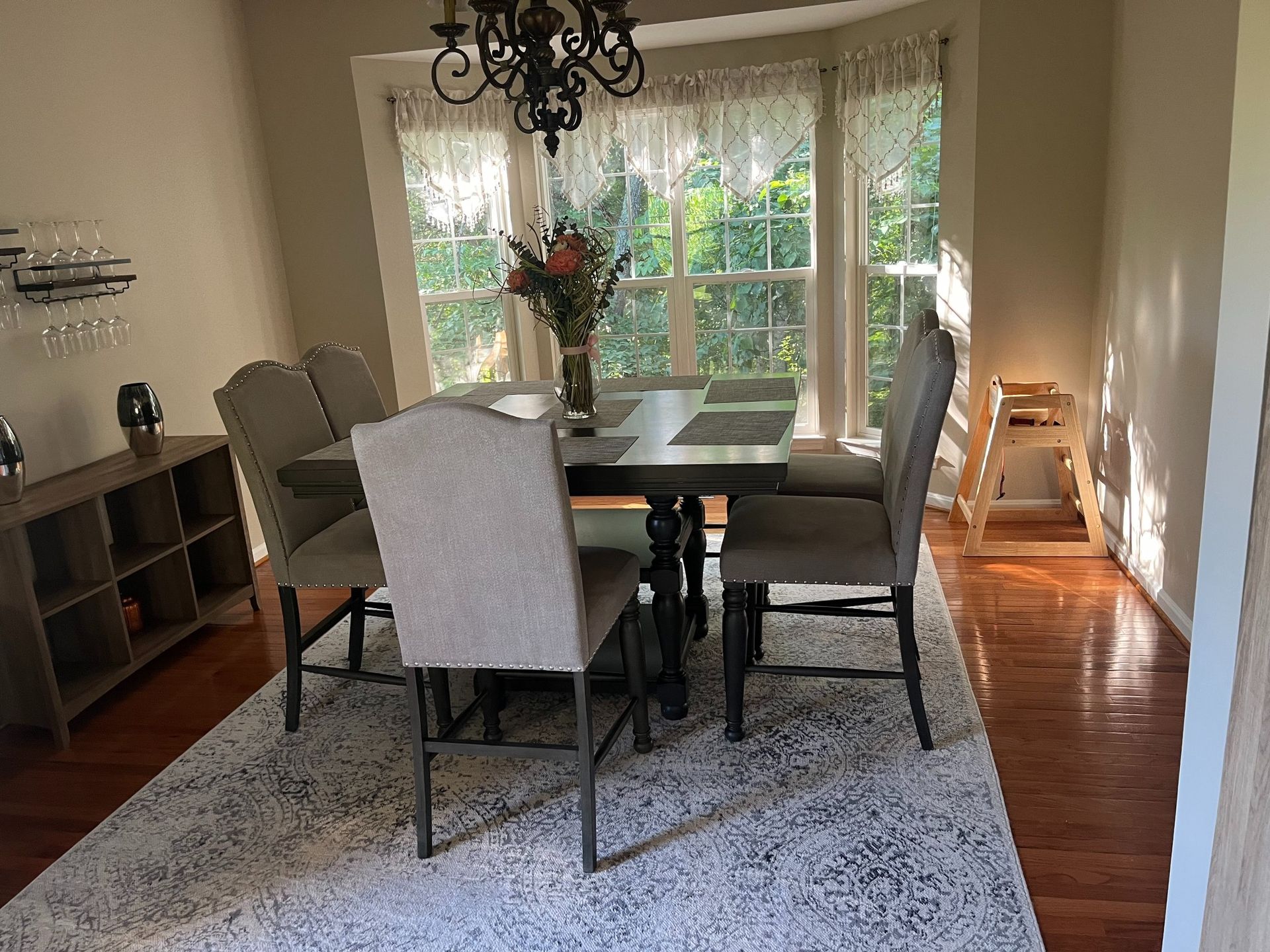 Dining room with a table, chairs, rug, cabinet, and a window with natural light.
