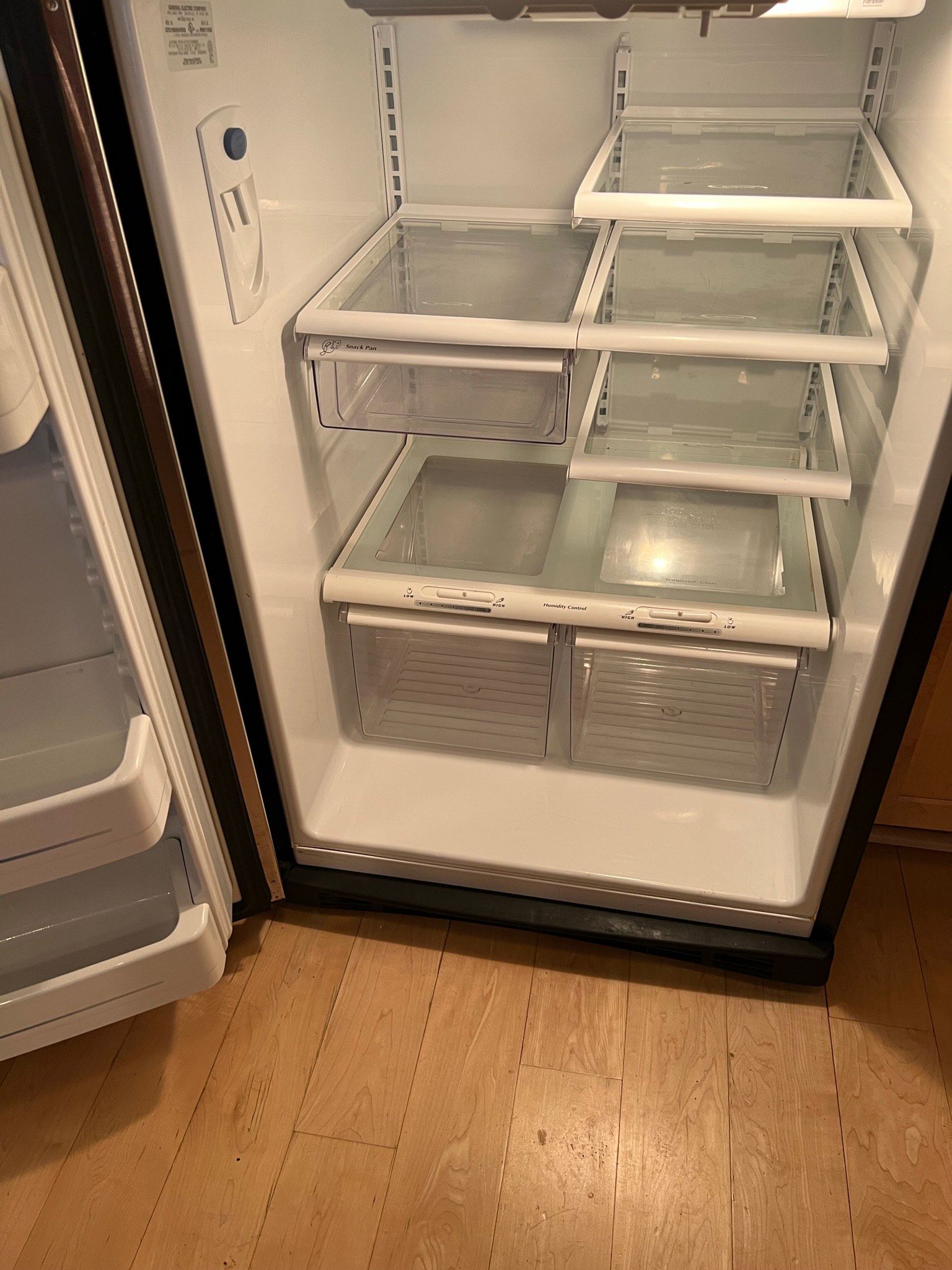 Empty, open refrigerator. Interior view with shelves, drawers, and lighting.