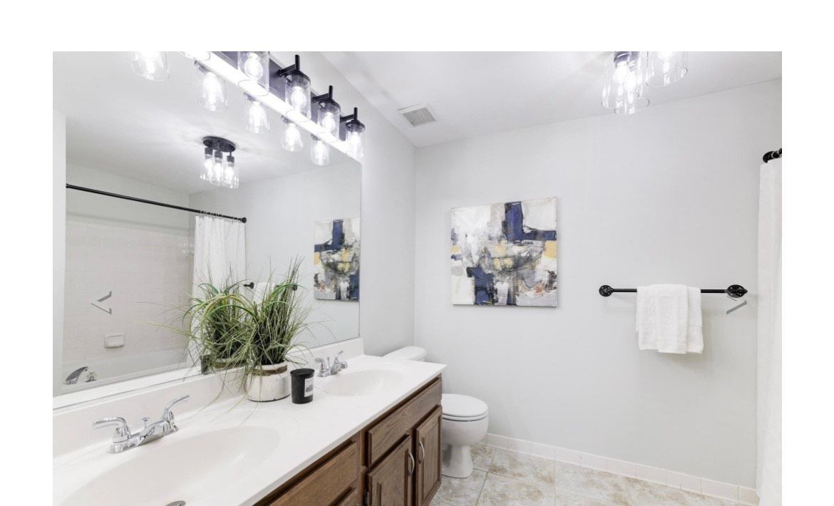 Bathroom with a long vanity, large mirror, and a piece of abstract art.