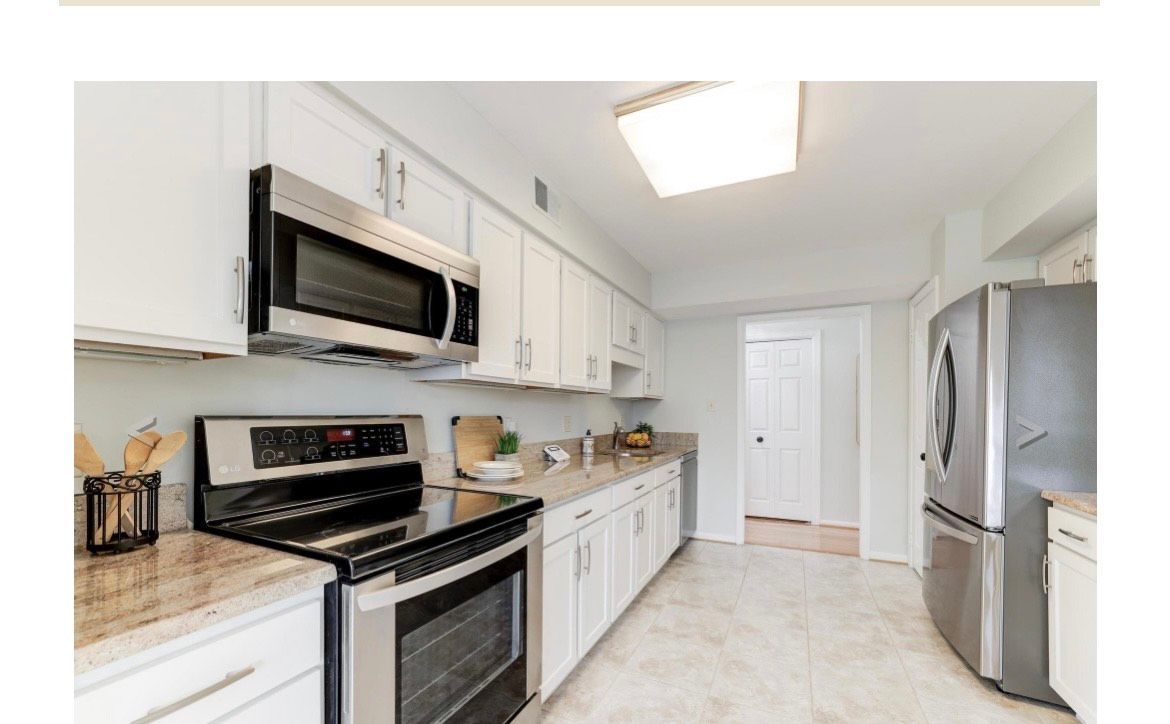 White kitchen with stainless steel appliances and light countertops.