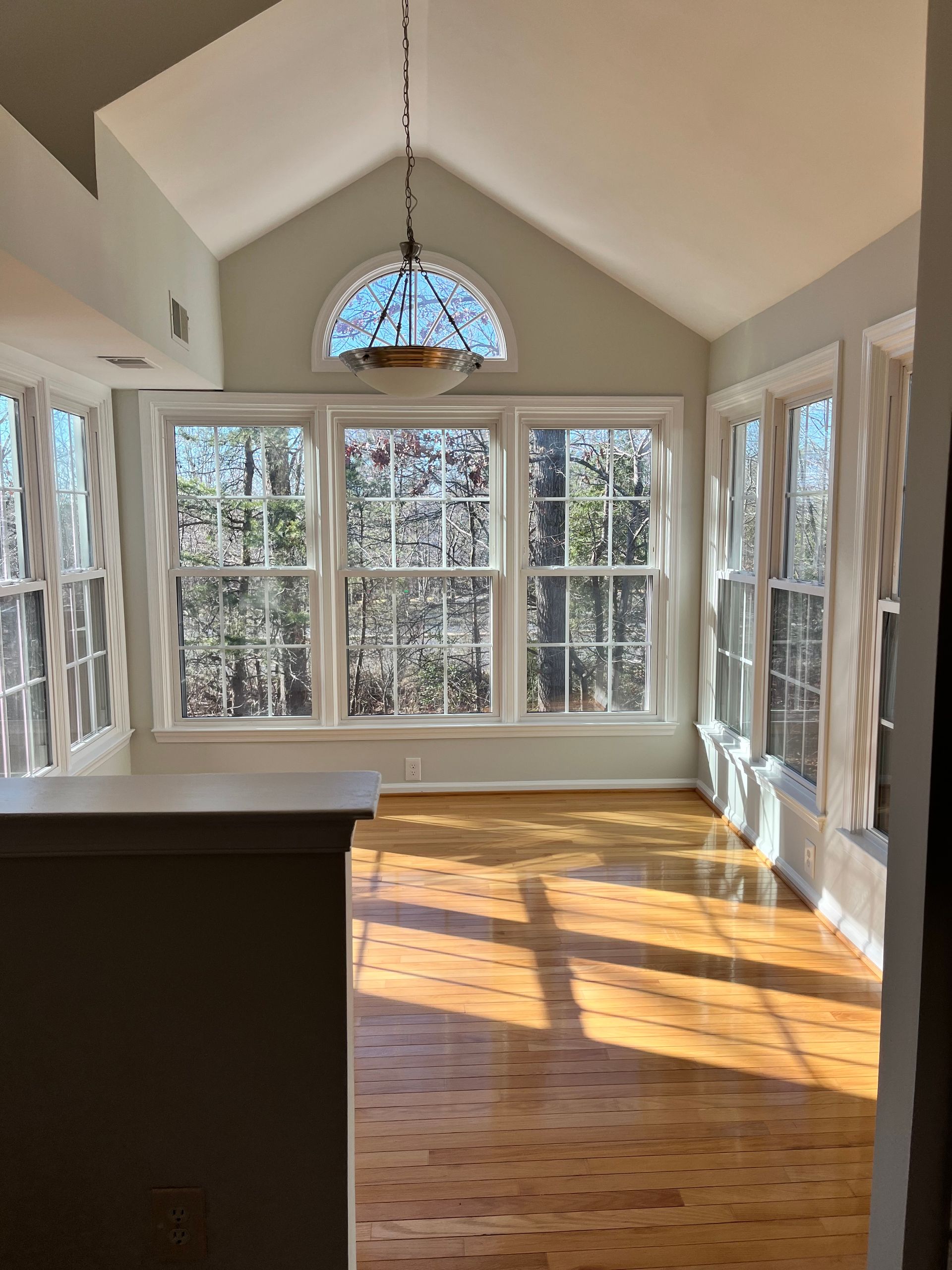 Sunroom with large windows and hardwood floors, sunlight streaming in.