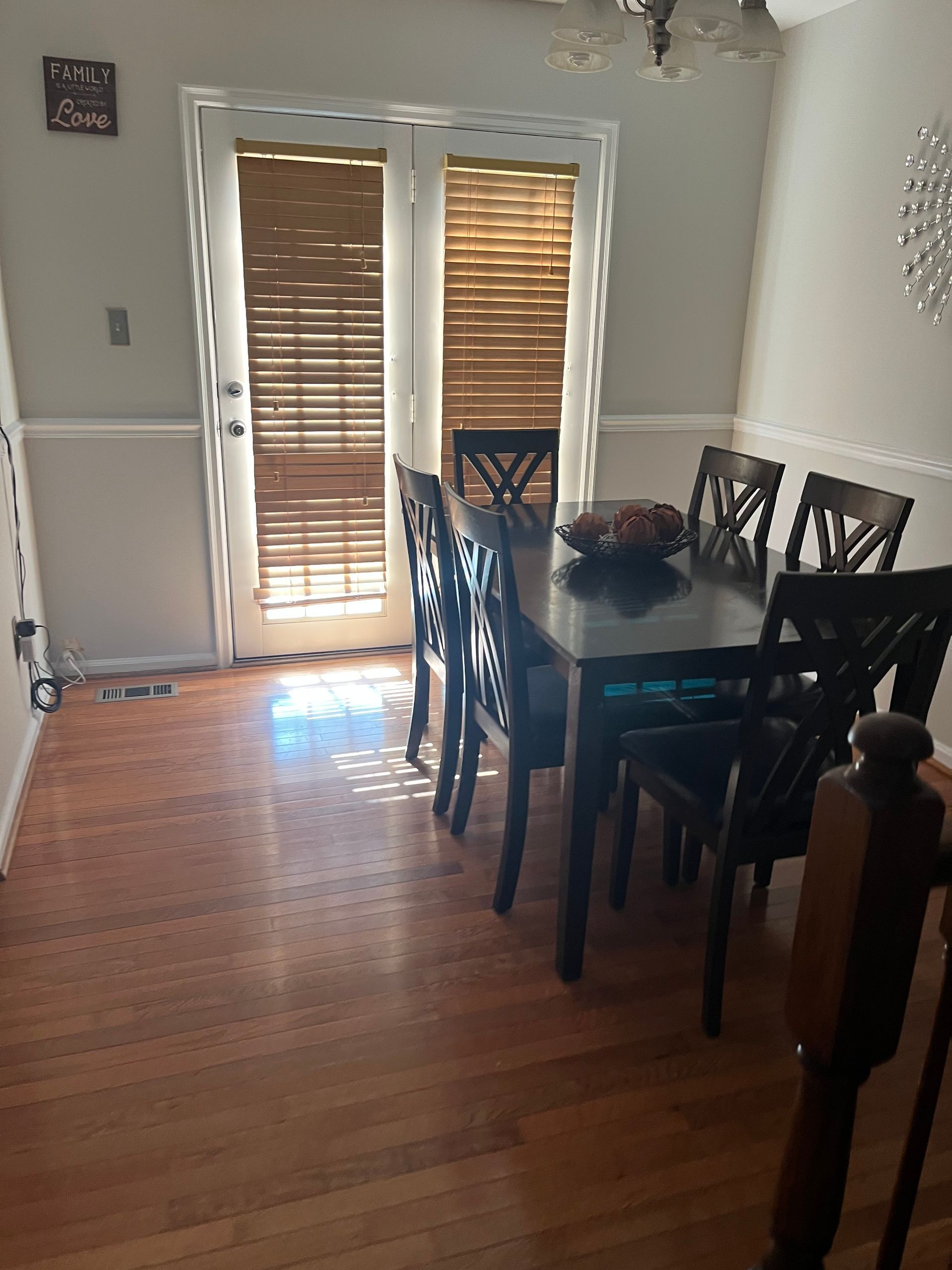 Dining room with a dark wood table and six chairs; wooden blinds cover the door.