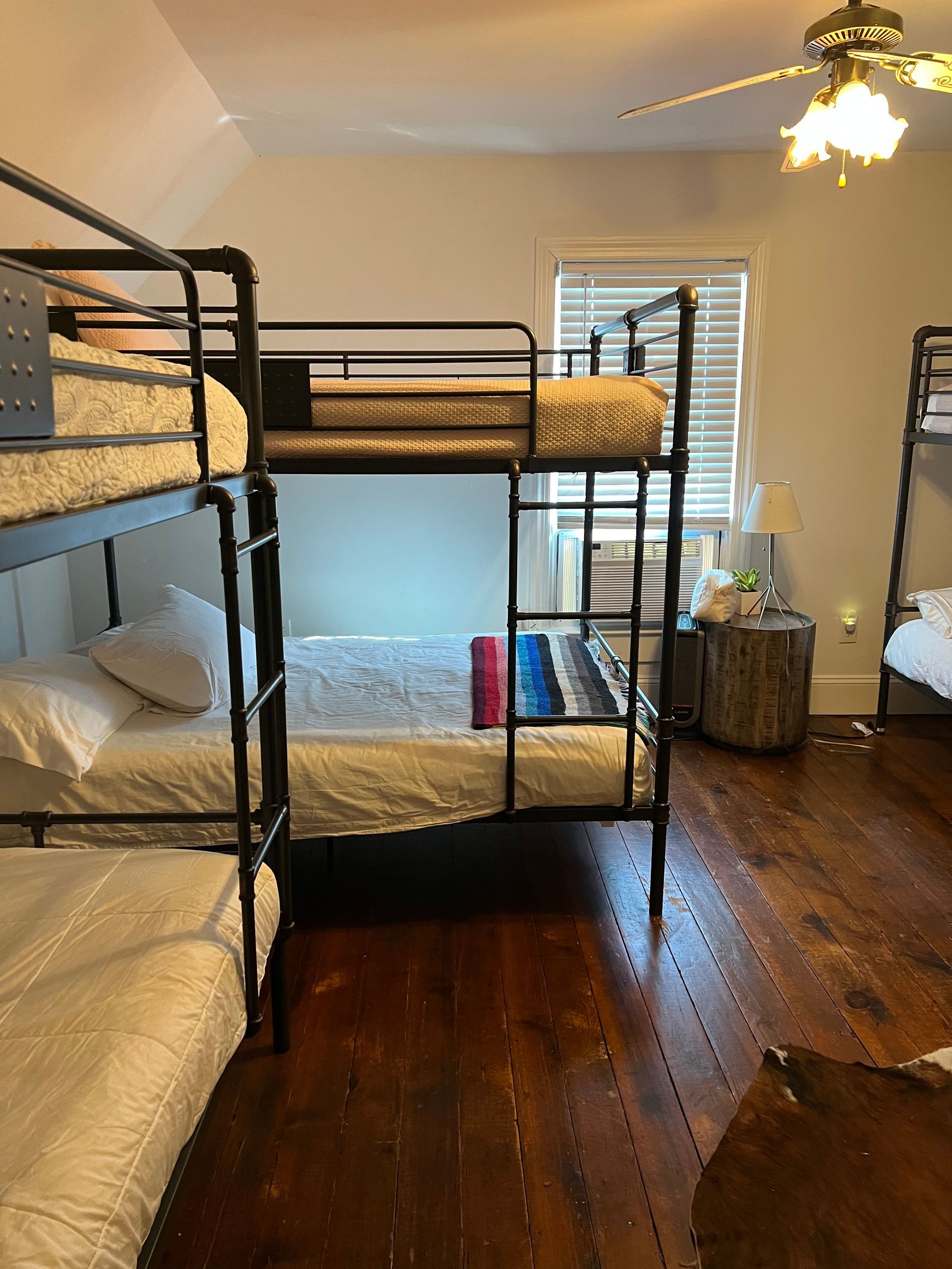Bunk beds in a room with wood floors and a ceiling fan; natural light from a window.