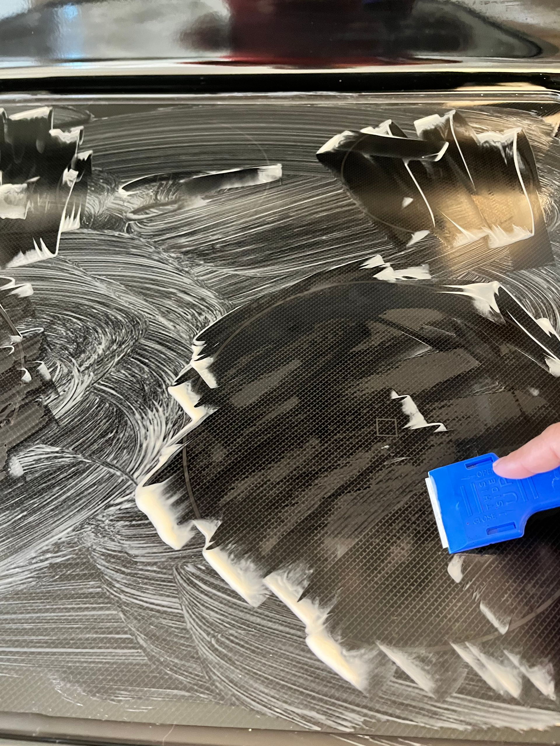 Carbon fiber surface being cleaned with soapy water and a blue squeegee.