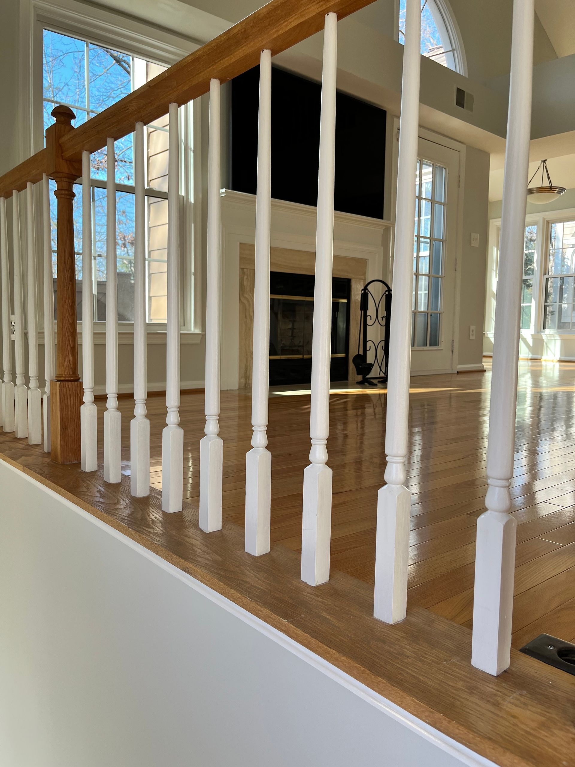 Wooden staircase with white spindles and a natural wood handrail.
