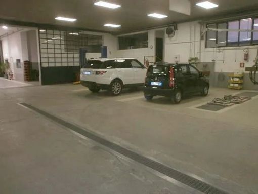 Un'officina con un SUV bianco e una berlina nera.