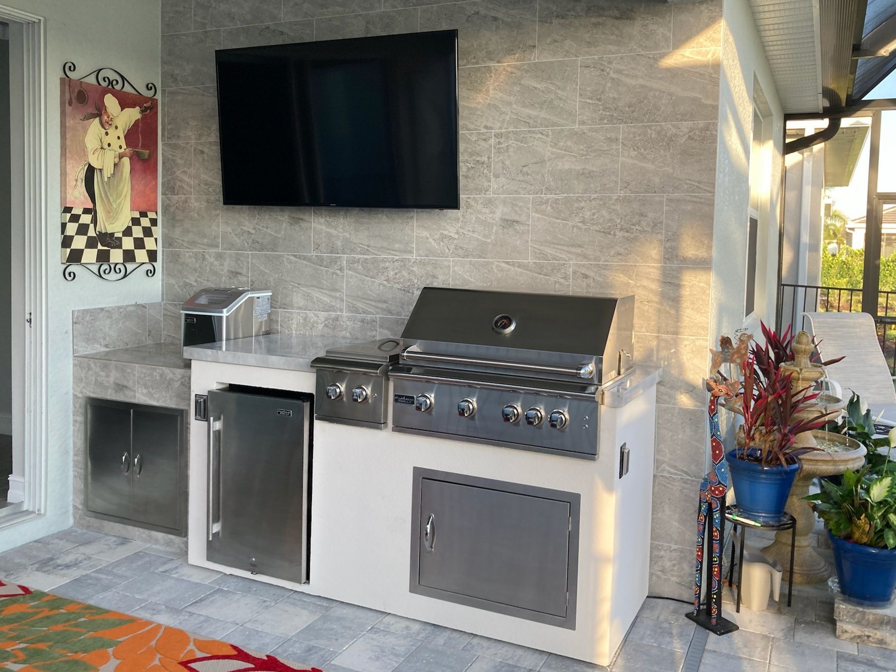 A kitchen with a grill and a flat screen tv on the wall.