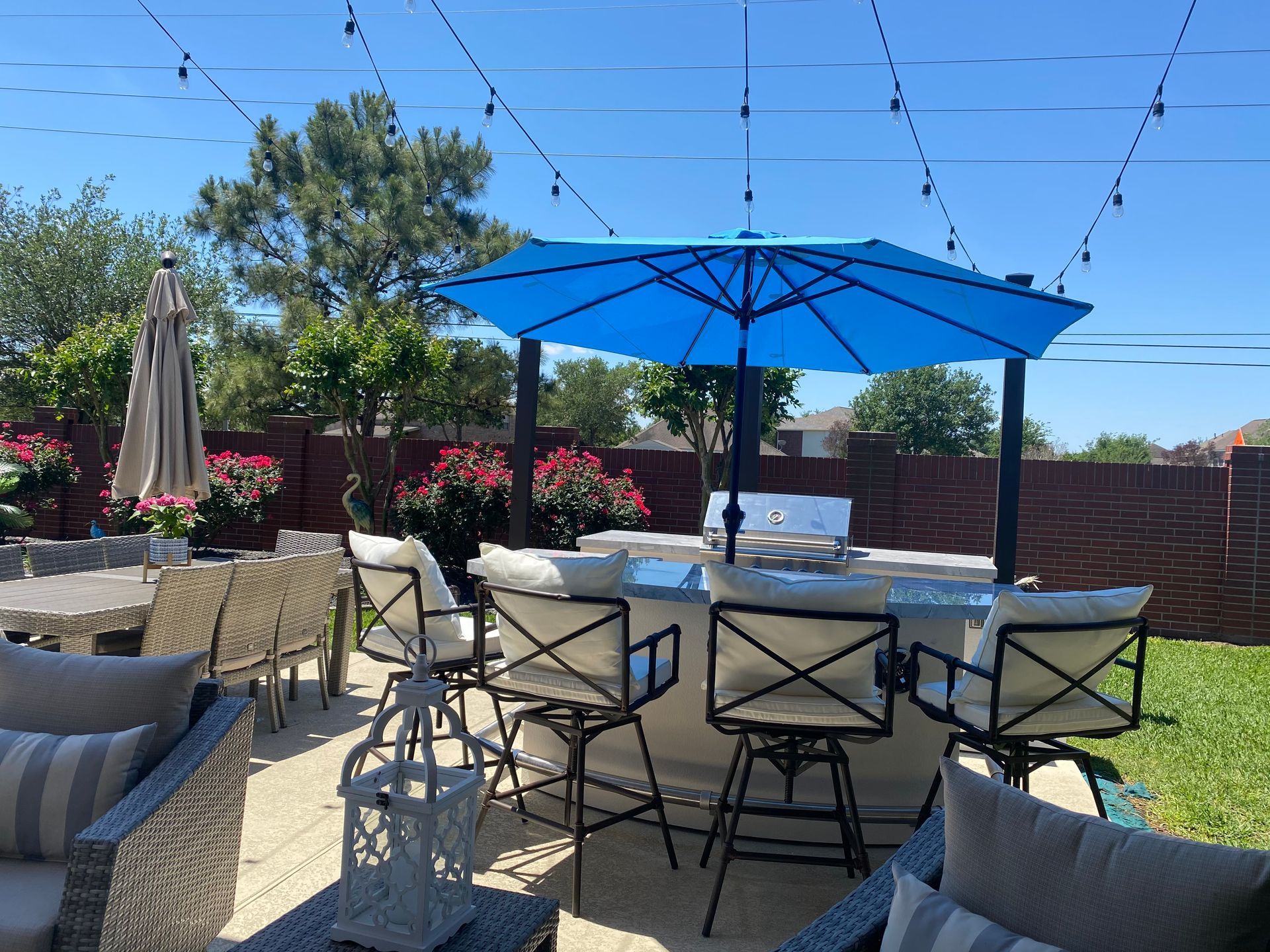 A patio with a table and chairs and a blue umbrella.