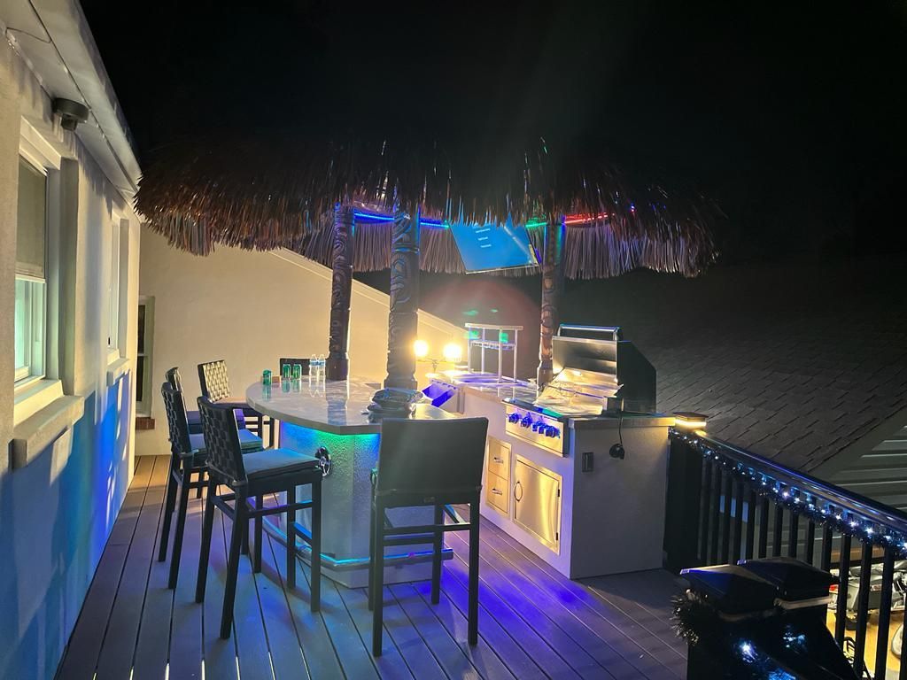 A deck with a table and chairs and a grill at night.
