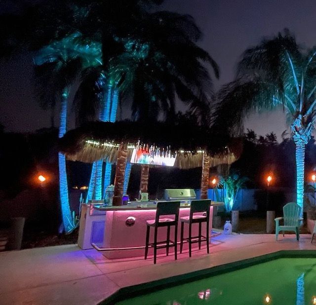 A swimming pool with a bar surrounded by palm trees