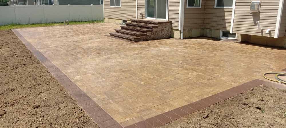 A patio with stairs and a house in the background.