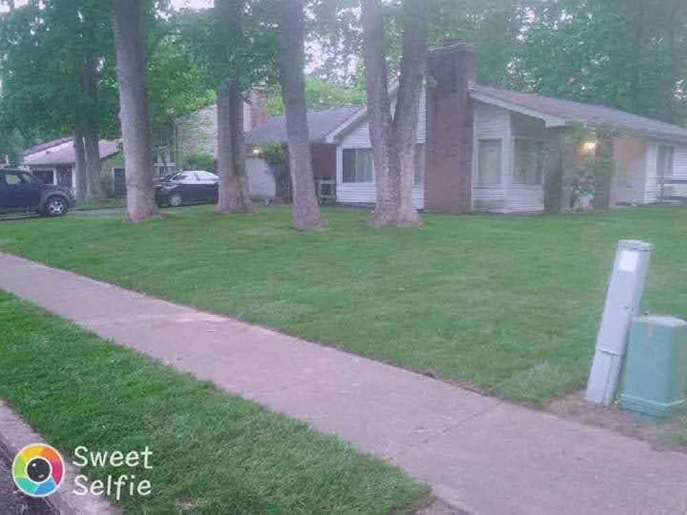 A house with a lush green lawn and a sidewalk in front of it.