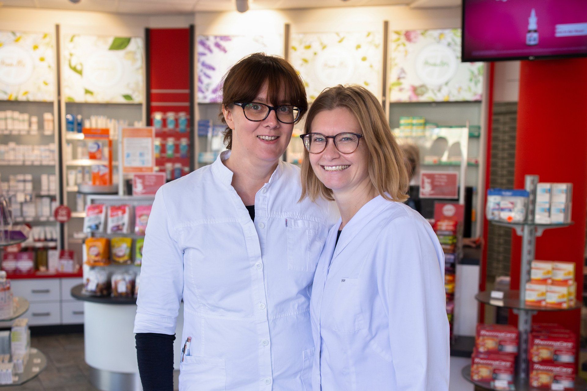 Zwei Apothekerinnen posieren in einer Apotheke für ein Foto.