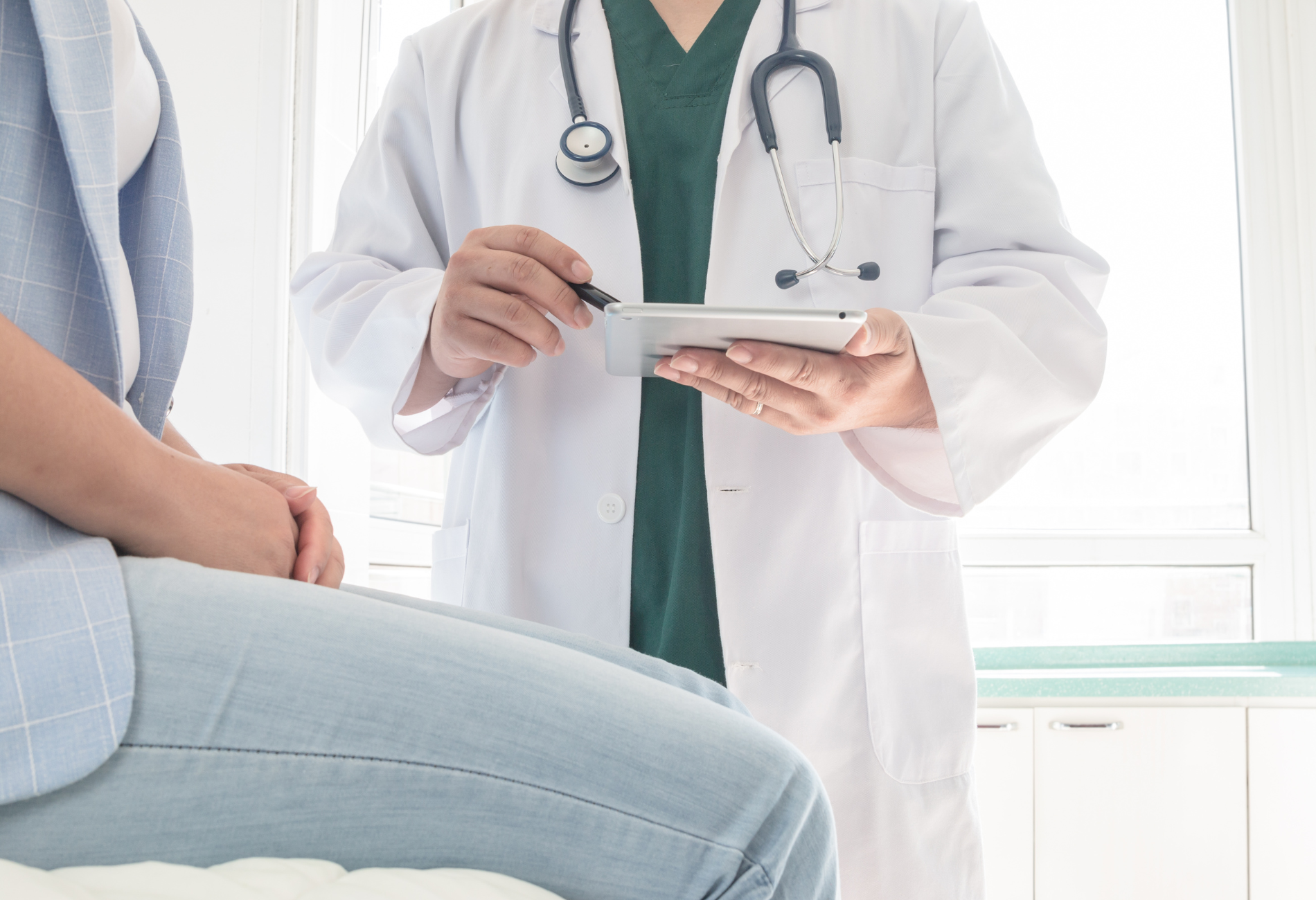 a doctor is talking to a patient while holding a tablet .