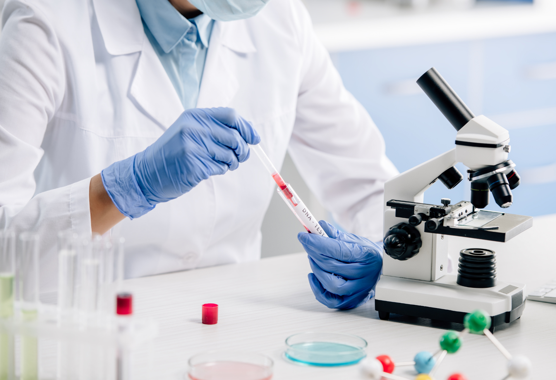 a scientist is holding a syringe in front of a microscope .