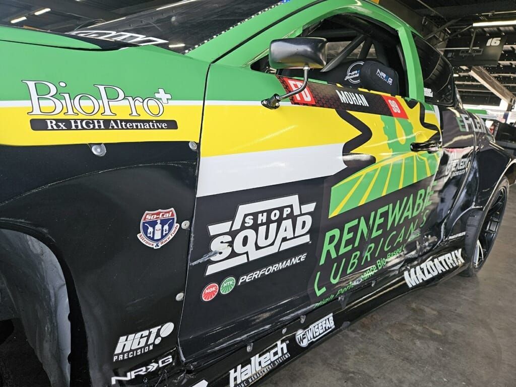 Green and black race car with sponsors' logos.