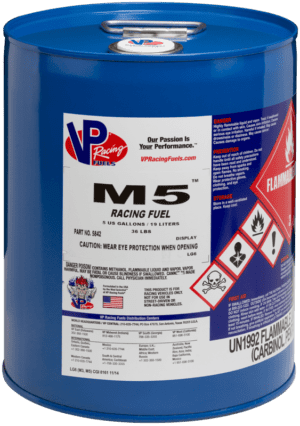 Blue VP Racing M5 Racing Fuel drum with hazard labels; white and red text, metal handle.