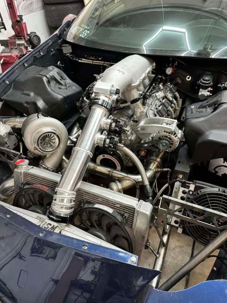 Blue car engine bay with a large turbocharger and custom cooling system.