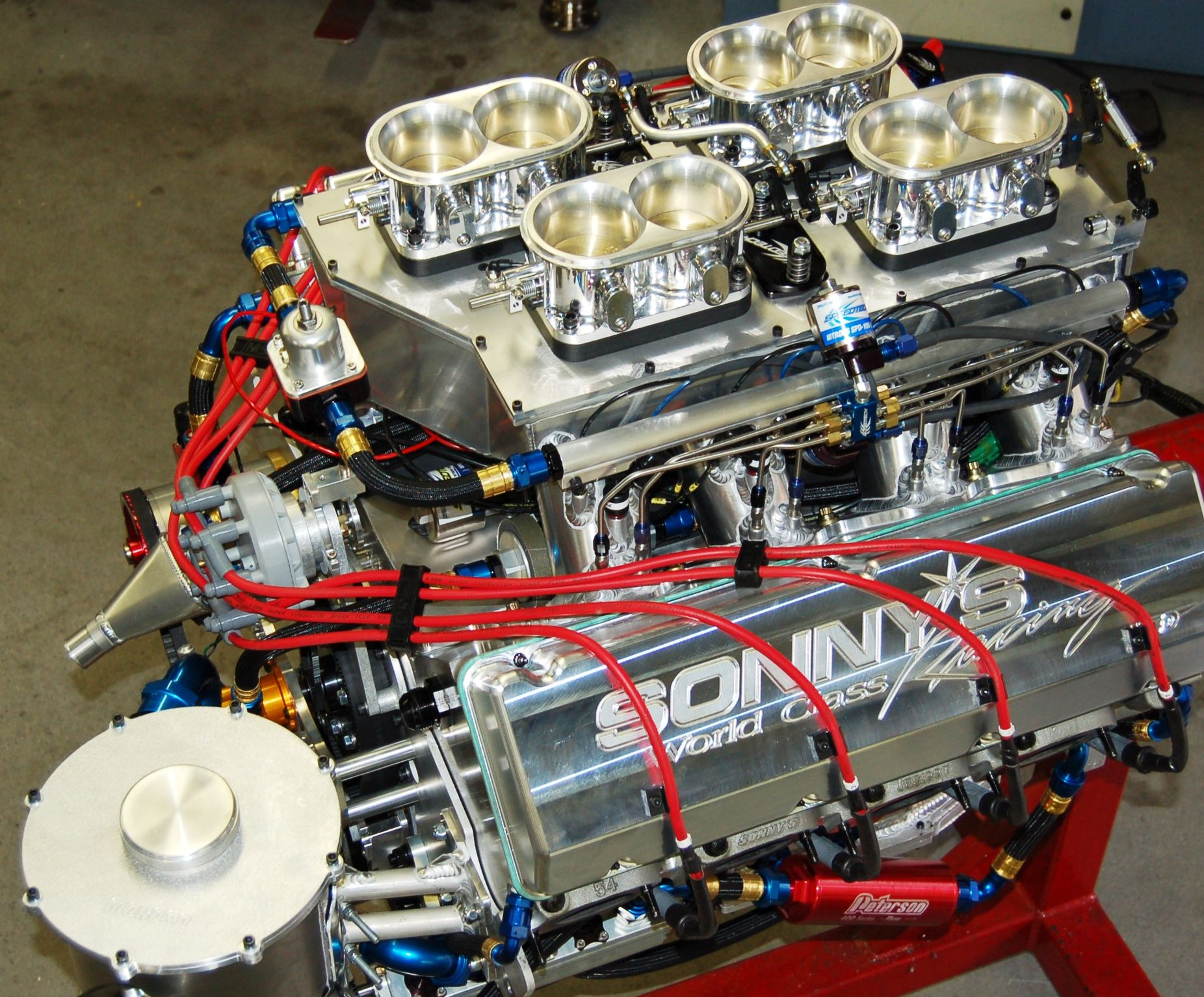 High-performance engine with four carburetors, fuel lines, and red spark plug wires.