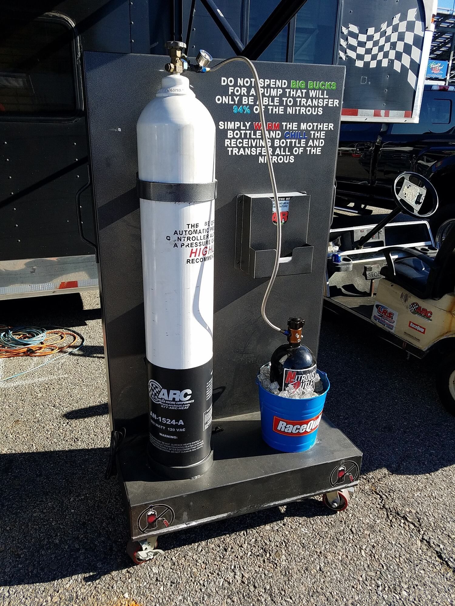 White gas tank with a beer bottle in a cooler on a wheeled platform. Sign above beer.