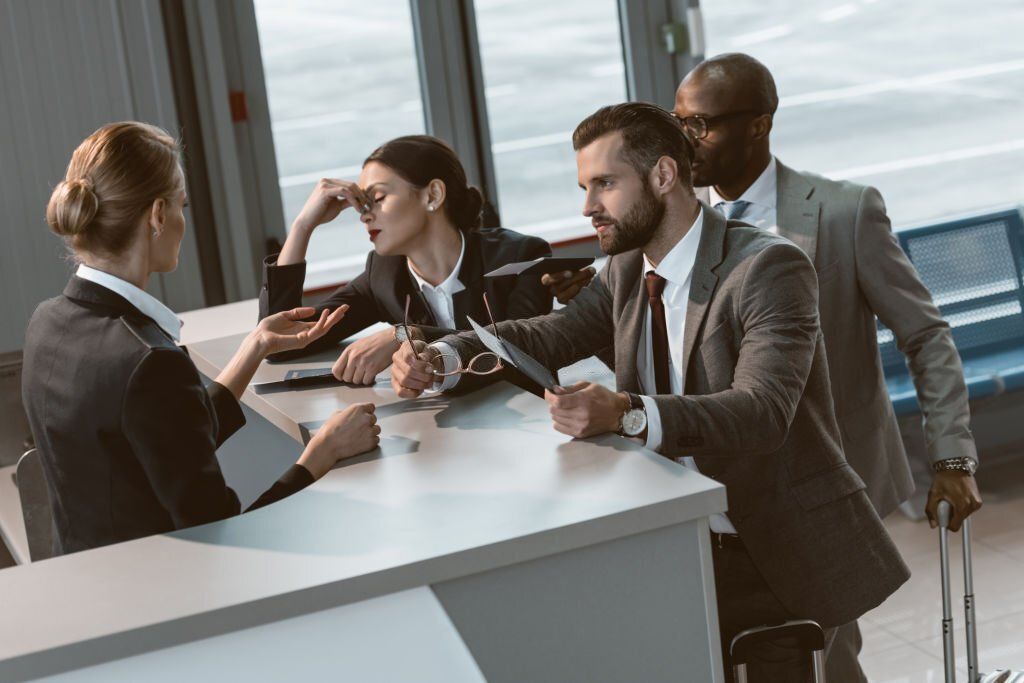 Frustrated group of business men and woman at the front desk and talking to a receptionist.