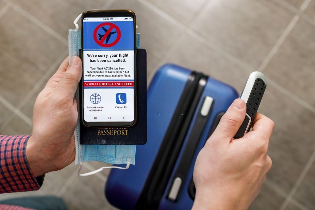 Person holding a mobile phone that says flight has been cancelled./