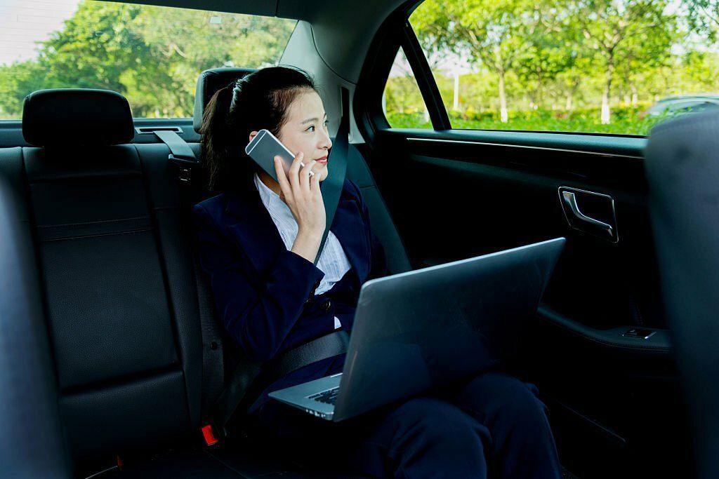 A beautiful businesswoman with a laptop sits in the backseat of a luxury car from Limo Hire Sunshine Coast.