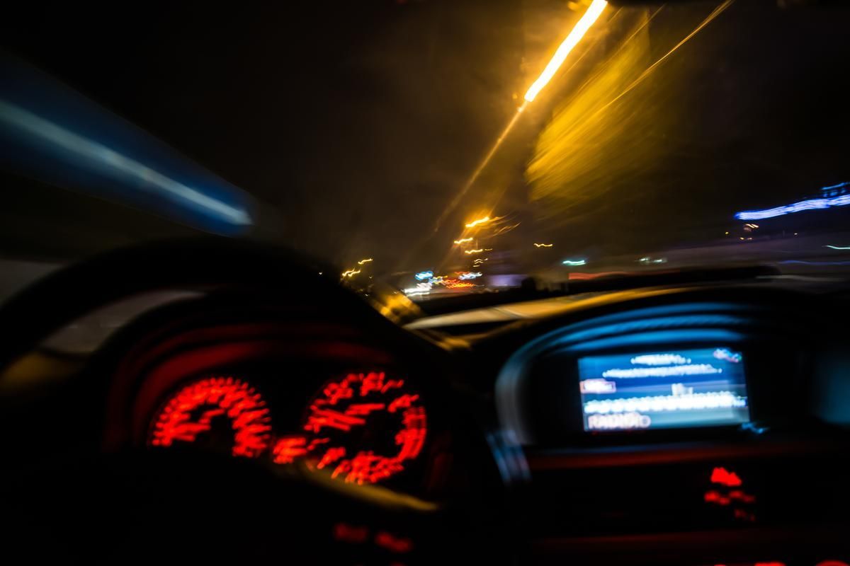 Blurred speedometer and background as car speeds at night.
