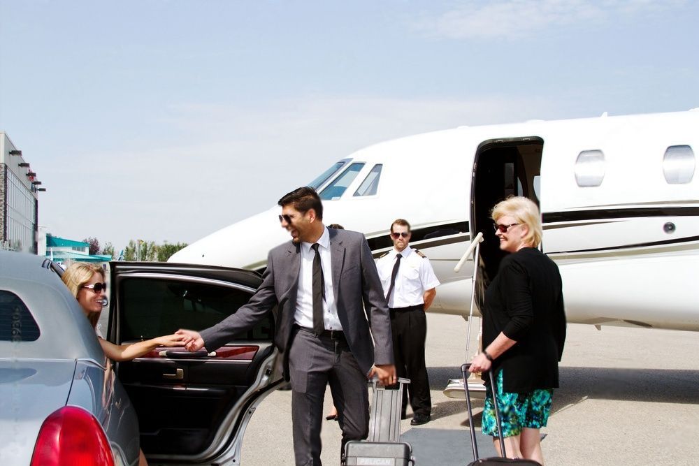 Corporate people getting out of a limousine to board a private plane.
