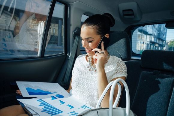 elegant business woman reviewing charts while on the phone inside a limousine by Limo Hire Sunshine Coast