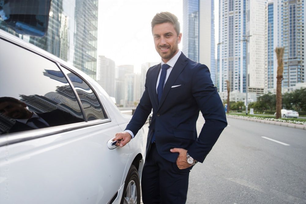 A handsome businessman is holding the door of a limousine from Limo Hire Sunshine Coast.