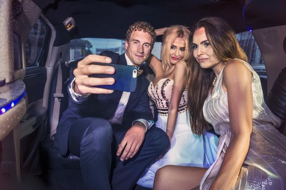 Three partygoers are taking a selfie inside a limousine by Limo Hire Sunshine Coast