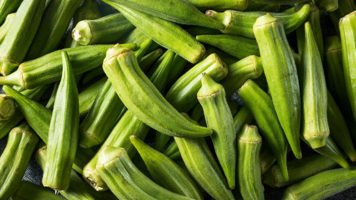Fresh green okra pods piled together, close-up view