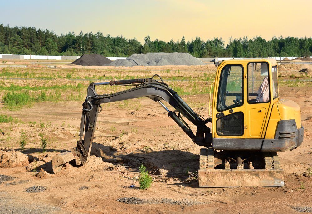 A Yellow Excavator Is Sitting In The Middle Of A Dirt Field — Mini Digger and Trailer Hire in Tablelands, QLD