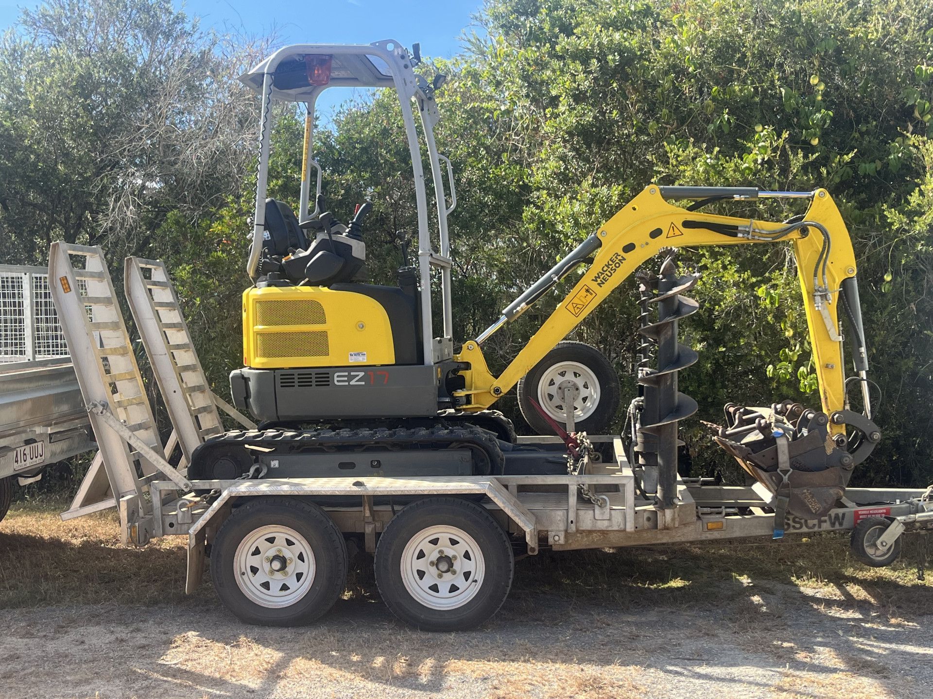 Yellow excavator on a trailer with auger attachment.— Mini Digger and Trailer Hire in Atherton, QLD