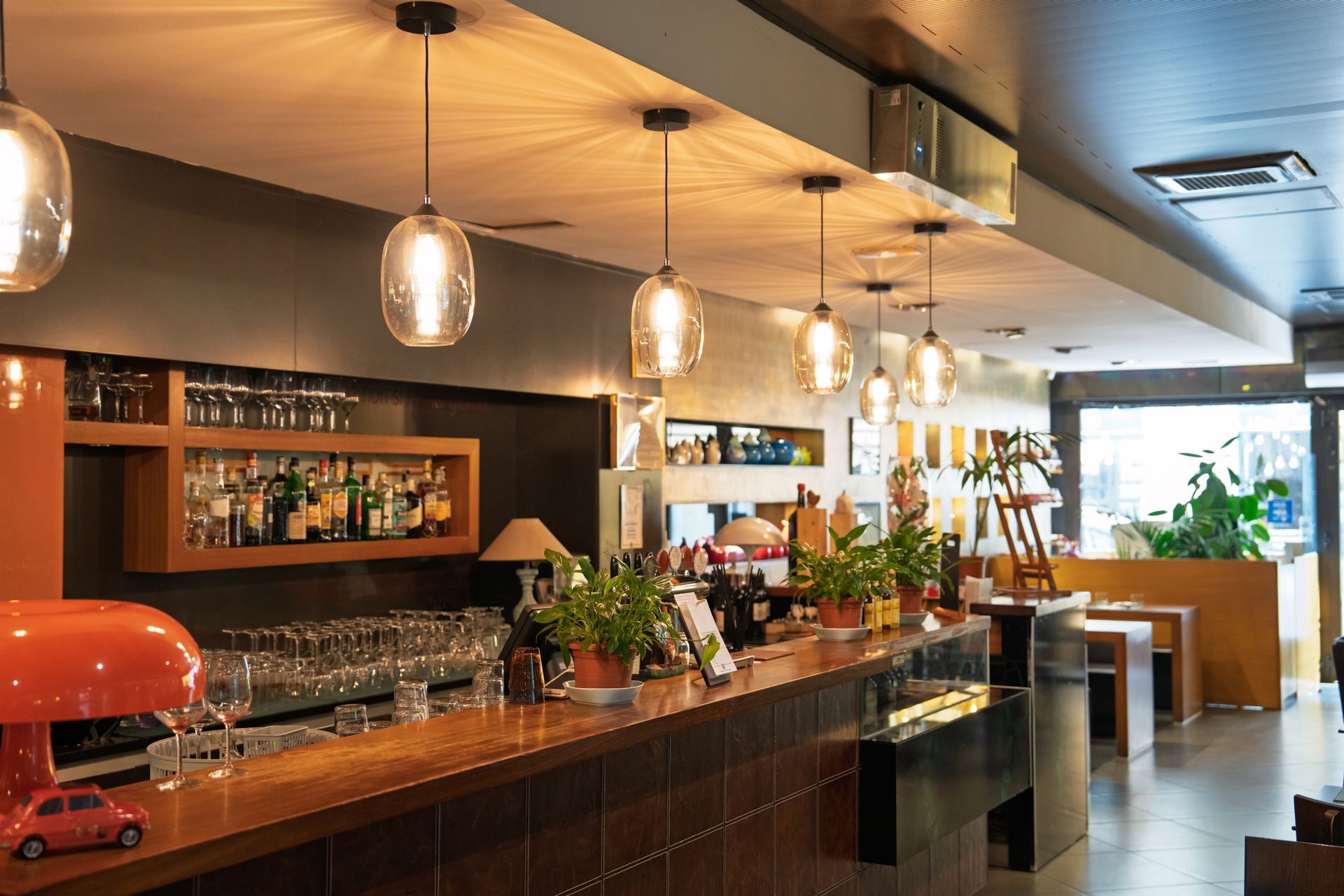 Warm pendant lights hang over a modern bar, creating a cozy and inviting restaurant ambiance. Warm pendant lights hang over a modern bar, creating a cozy and inviting restaurant ambiance.