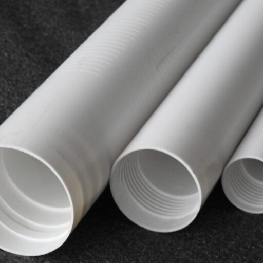Four white plastic pipes are stacked on top of each other on a black surface.
