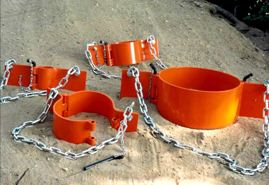 A white pipe is hanging from a chain in a field.