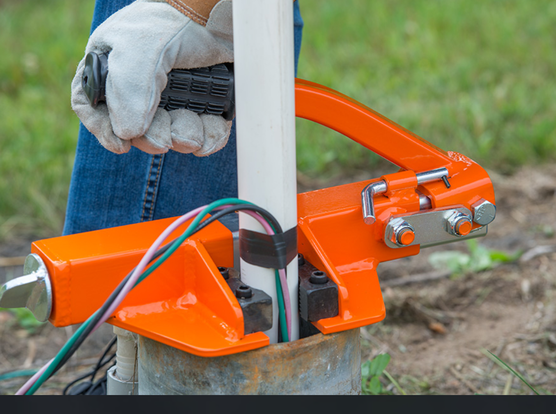 A red object with a black handle is attached to a metal pipe